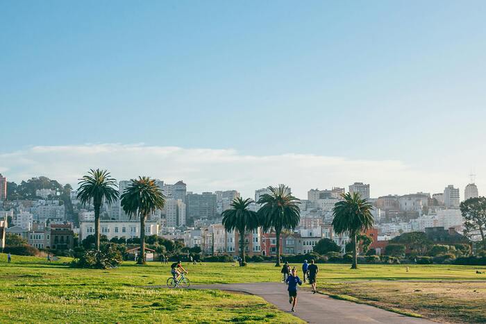 Imagem de parque com natureza e pessoas se exercitando.